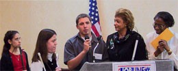 A young man accepts his award at the podium surrounded by other members.