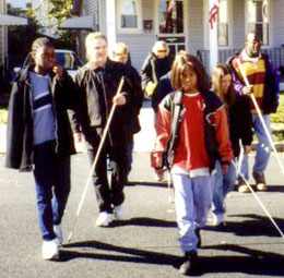 Students and mentors walk across the street using their canes.