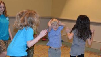 A group of blind and sighted kids jump around together during a convention gathering.